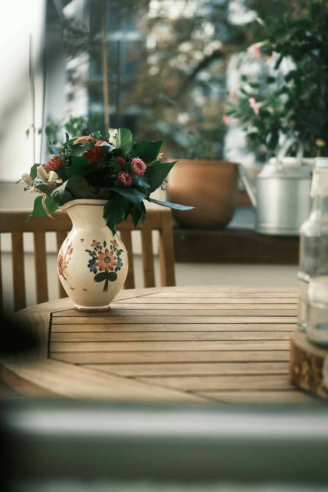 Vase of flowers on a wooden table outdoors.