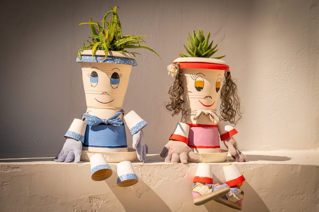 Two quirky plant pots shaped like people sitting together