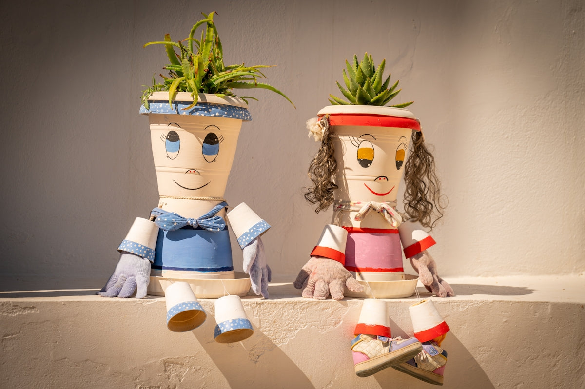 Two quirky plant pots shaped like people sitting together